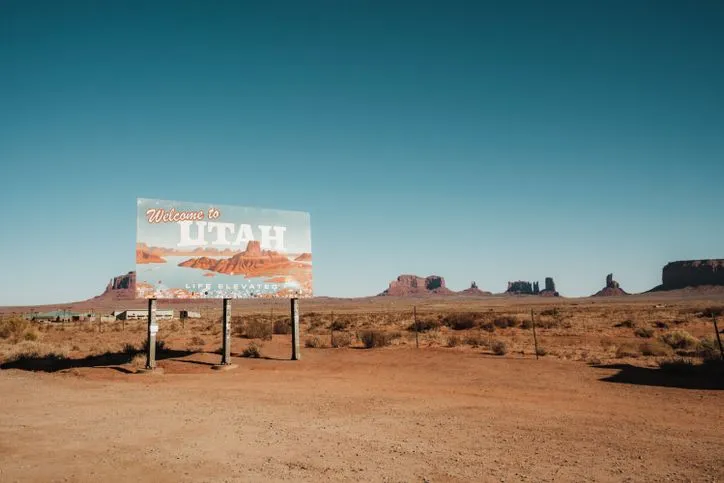 Explore the arid beauty of Monument Valley with the iconic Utah welcome sign under a clear sky.