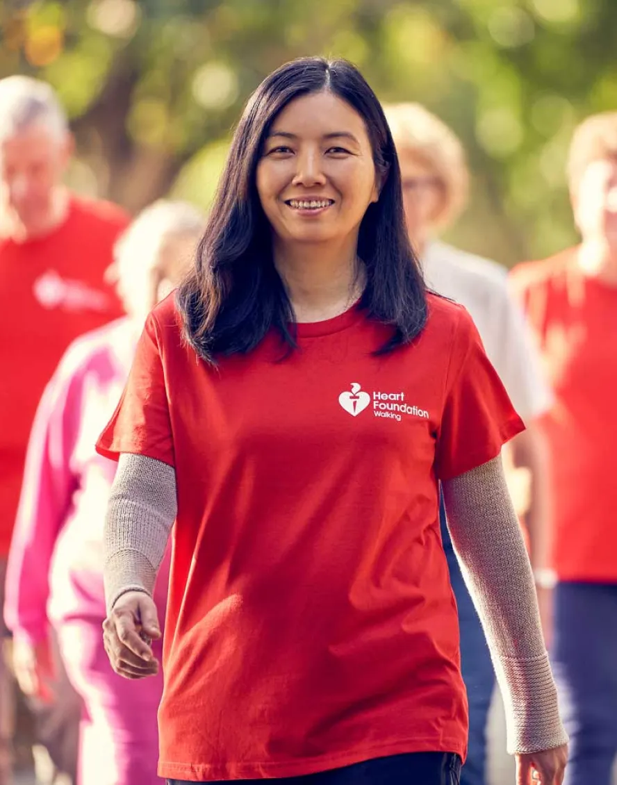 A group of people wearing Heart Foundation tees walk in a park.