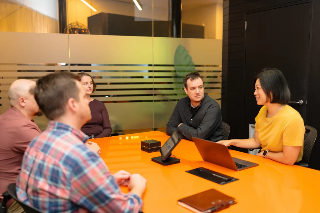 Avion team having a discussion around a conference table in a meeting room.